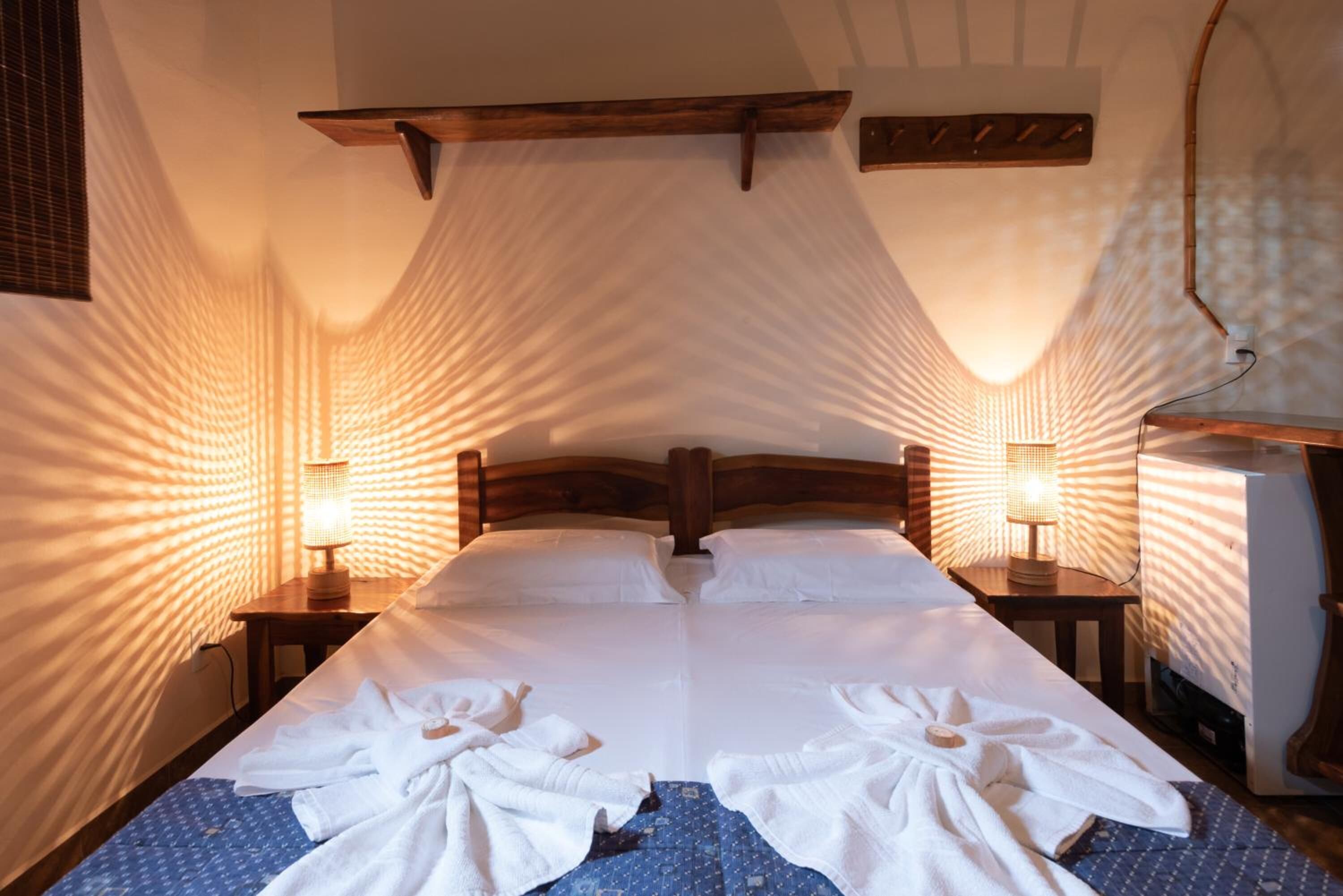 Quarto de hotel com uma cama grande, duas mesas de cabeceira e um dossel.
