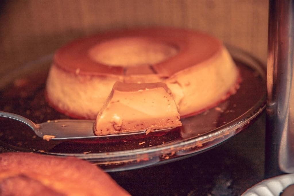 Un postre en un plato, posiblemente un flan o un pudín de caramelo, con una porción cortada.