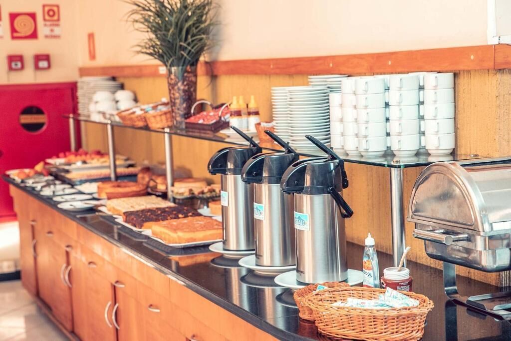 Tarjolla on runsas buffet, jossa on monenlaista ruokaa, kahviautomaatteja ja mehujen kylmälaitteita.