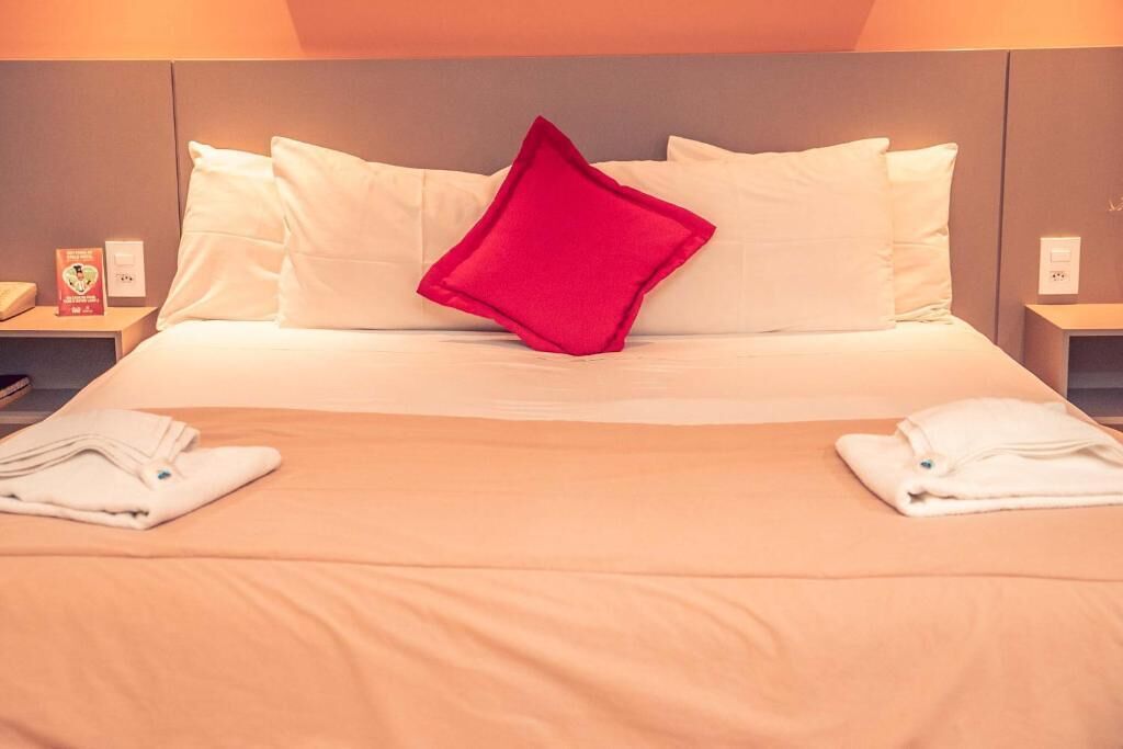 A hotel room with a bed, pillows, and folded towels on the bed.