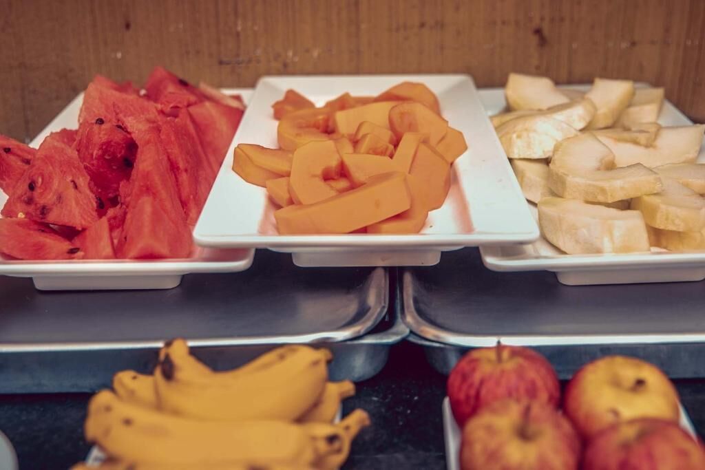Tres bandejas con frutas cortadas: sandía, melón y plátanos.