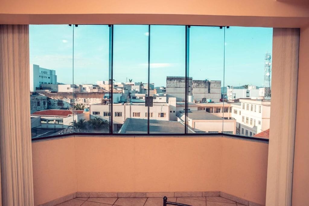 A room with a large window offering a view of a cityscape.