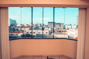A room with a large window offering a view of a cityscape. - Stalo Hotel (Piumhi)