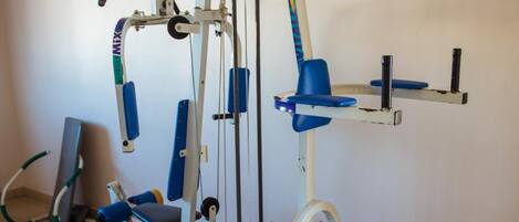 Un gimnasio con una máquina de ejercicio multifuncional, una banca y una estructura para sentadillas.