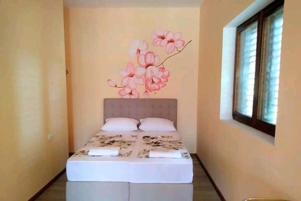 Un dormitorio con cama, ventana y pared con un mural floral.