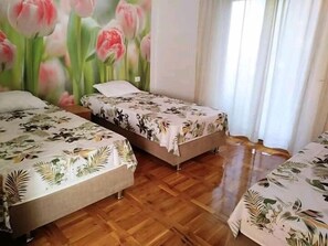 Huoneessa on kaksi sänkyä, joissa kummassakin on kukkakuviollinen peitto, puulattia ja suuri, seinälle maalattu kukkateemainen seinämaalaus.