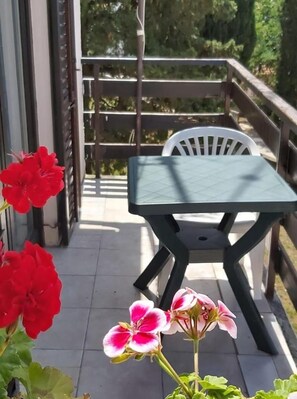 A balcony with a table and chairs, surrounded by greenery and flowers. - Rooms Svitlana (Sukosan)