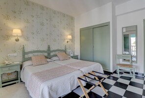 Un dormitorio con dos camas, piso a cuadros y un armario verde.