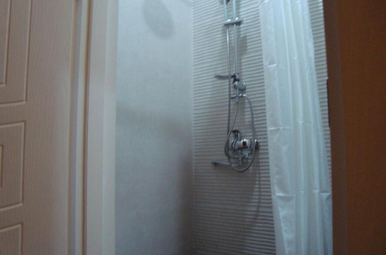 A bathroom with a shower enclosure, a door, and a towel rack.