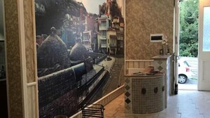 A hallway with a mural of a cityscape, a chandelier, and a tiled floor. - Old Tbilisi Historical Apartments (Tbilisi)