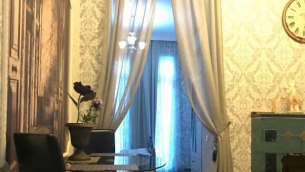 A room with a checkered floor, a dining table with chairs, a large painting on the wall, and a clock. - Old Tbilisi Historical Apartments (Tbilisi)