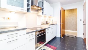 A modern kitchen with white cabinets, a built-in oven, and a countertop with a toaster. - Waterside Bliss  Austin David Apartments (London)