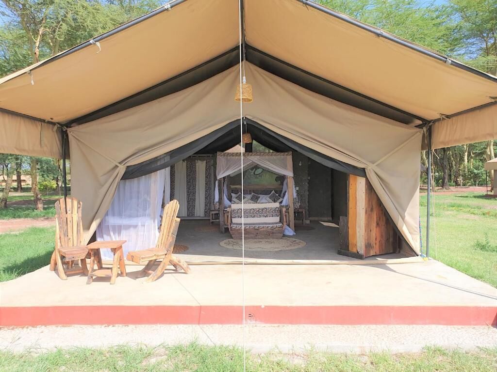 Una carpa con una cama, dos sillas de madera y una lámpara colgante.