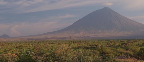A mountain landscape with a prominent peak and a flat, green area in the foreground.