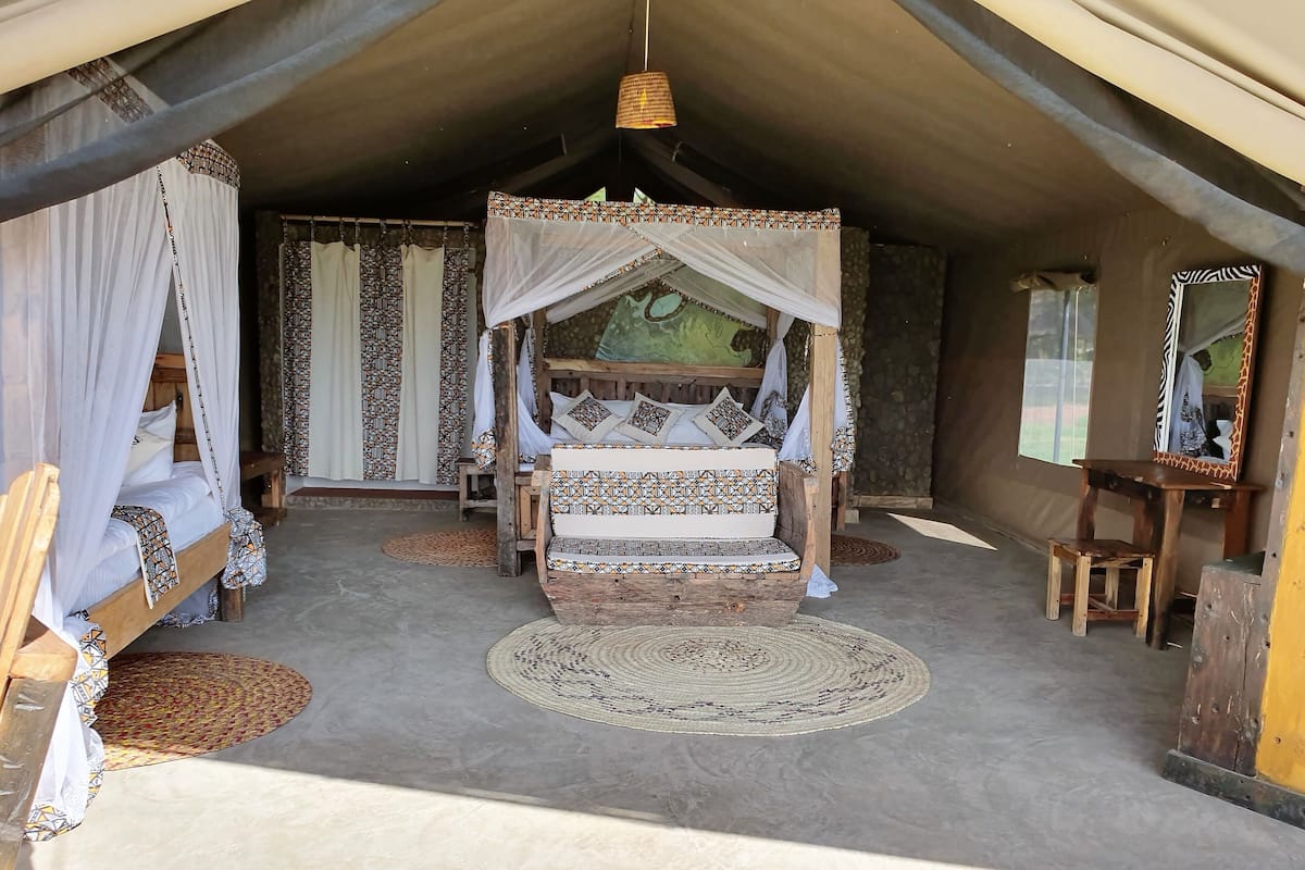 Een tentaccomodatie met een bed, een klein tafeltje en een spiegel.