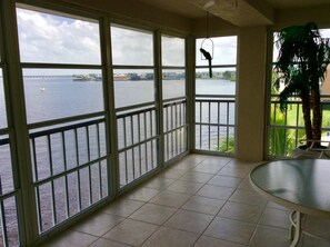 A balcony with a view of a body of water, a hanging bird feeder, and a potted plant.