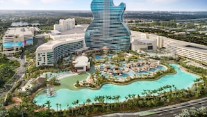 A resort with a guitar-shaped building, a large pool, and multiple guest villas.