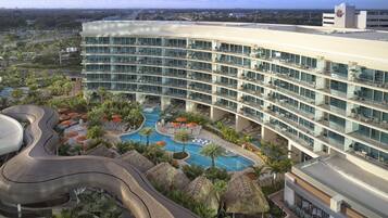 Un hotel moderno con zona de piscina, varios balcones y vistas de la ciudad circundante.
