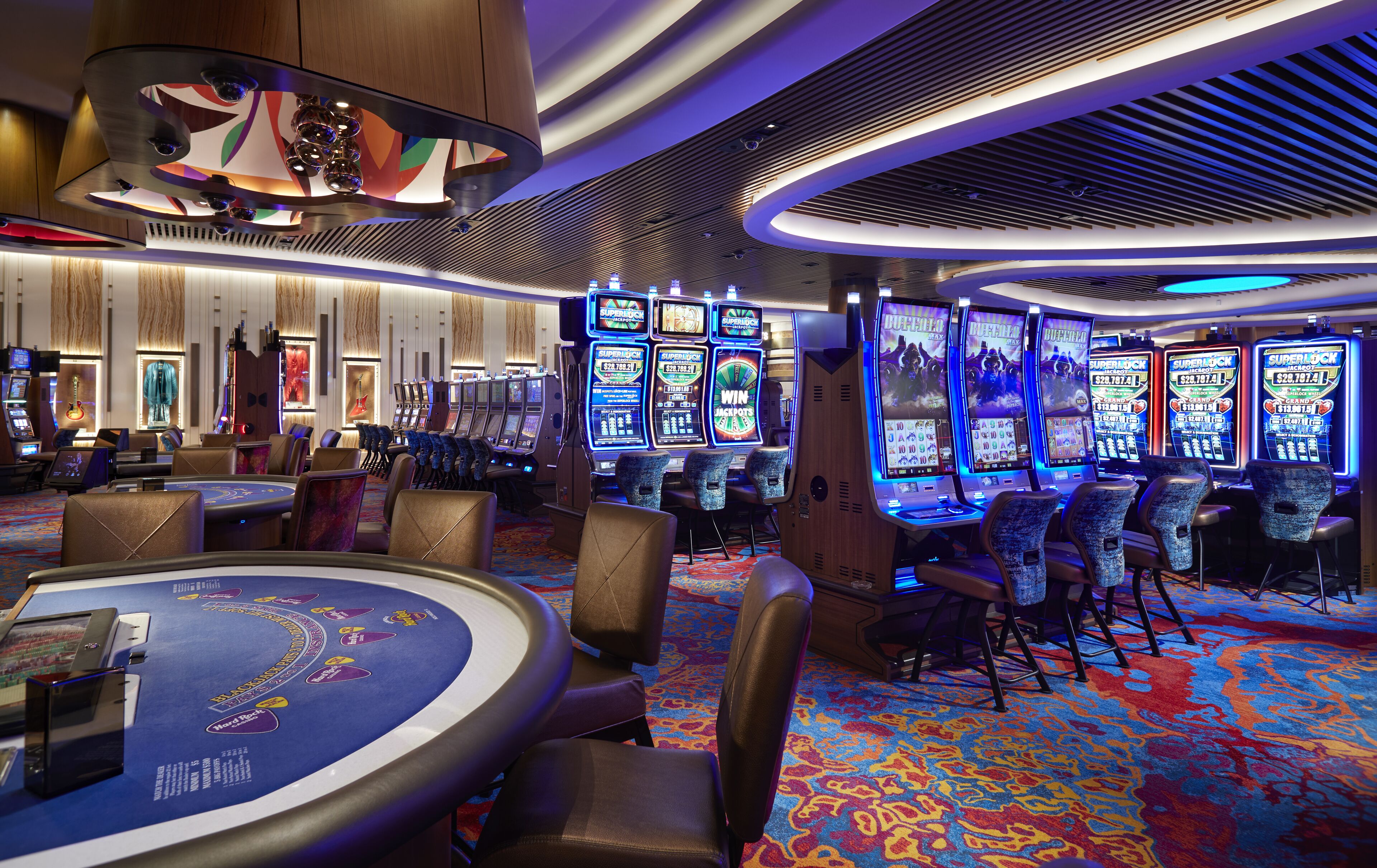 Un casino con numerosas máquinas tragamonedas, una mesa de blackjack y asientos cómodos.