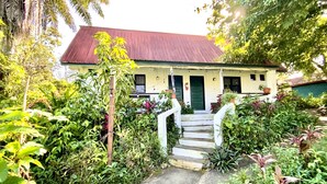 A house with a red roof, white walls, and a small porch with steps leading to the door.
