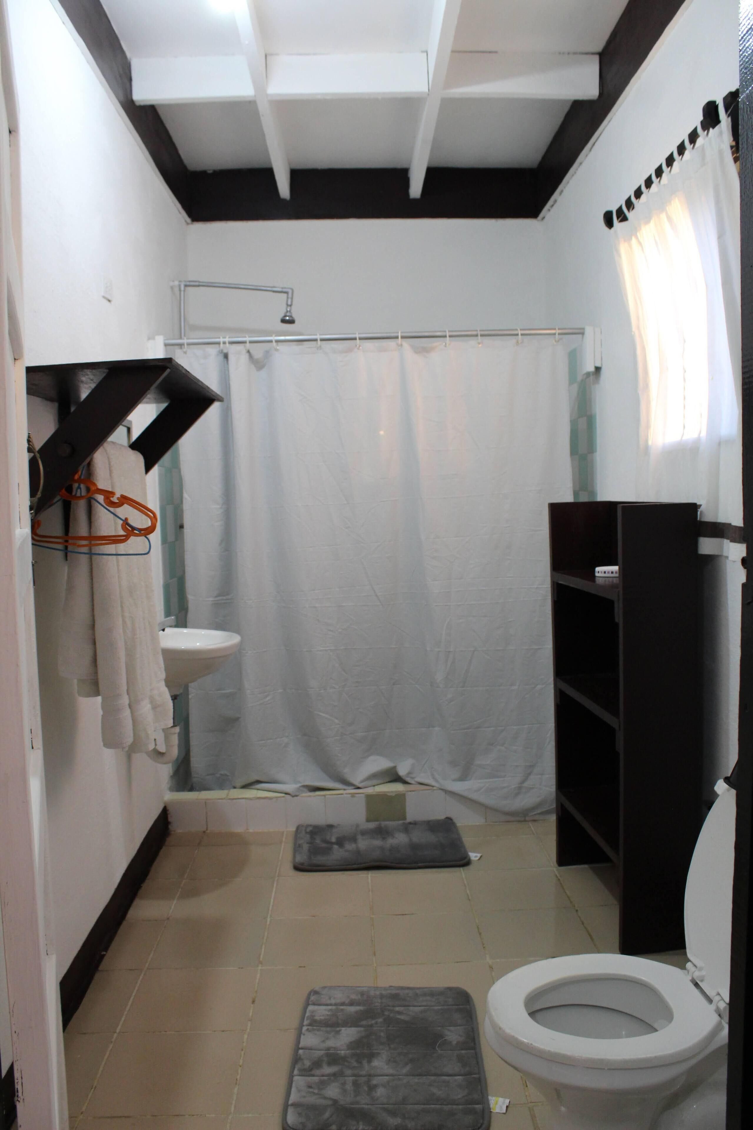 A small, compact bathroom with a white sink, toilet, and shower curtain.