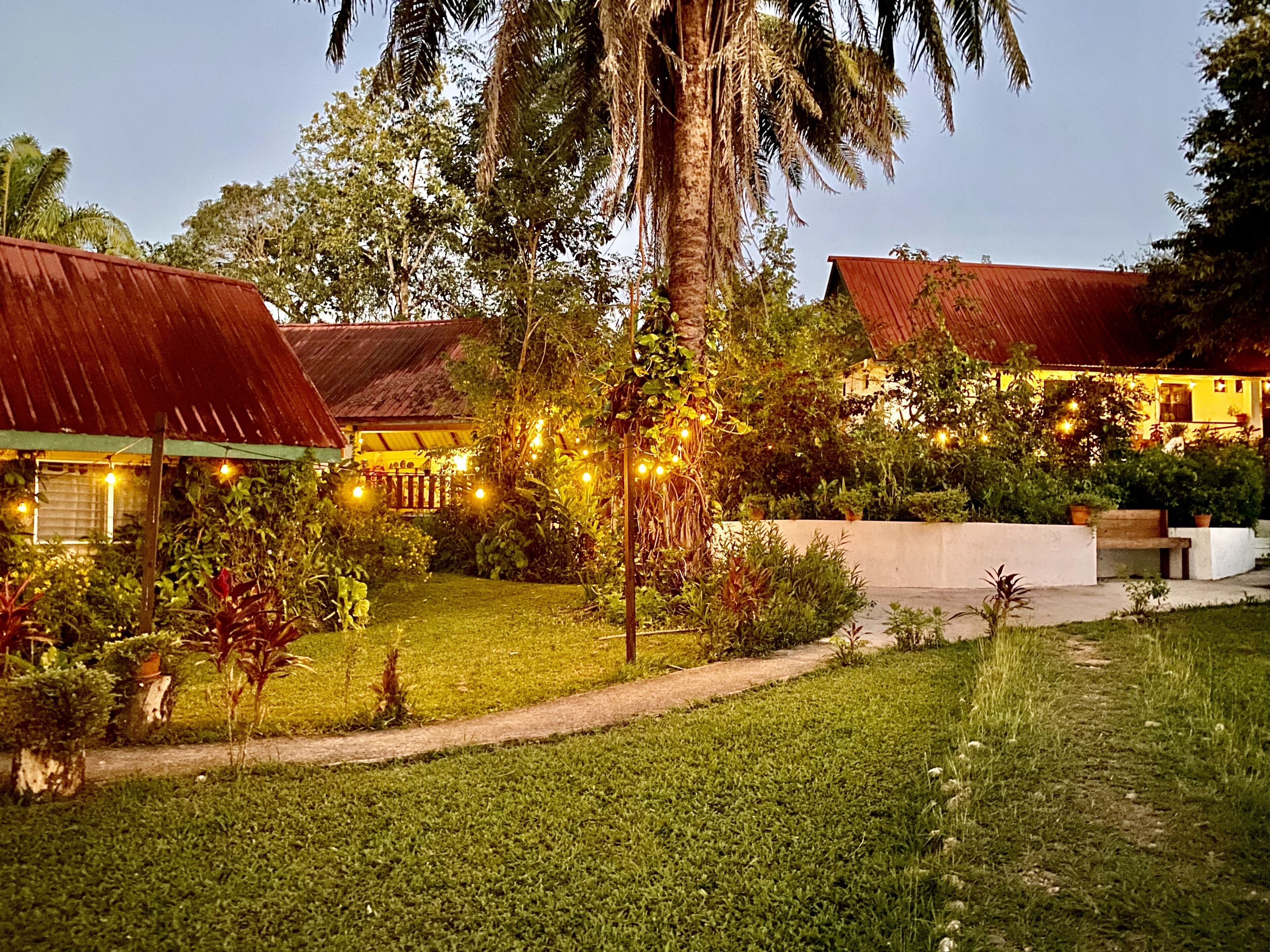 A well-maintained garden with a pathway leading to a building with a red roof.