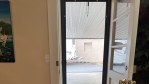 A door leading to a parking area with a view of a building and a parked vehicle.