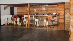 A modern interior with a bar area, wooden stools, and a stone-tiled floor. - Family apartment in Saint-Lary for 6 people, near the gondola and thermal baths. (Saint-Lary-Soulan)