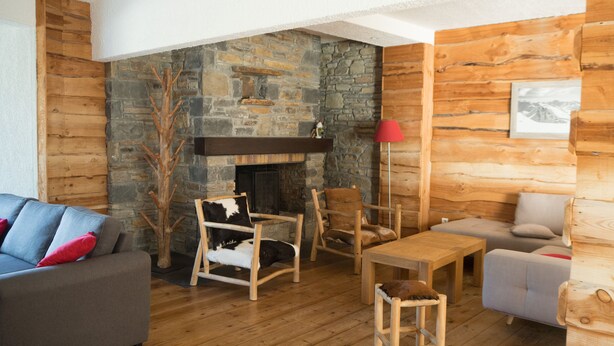 A cozy living room with a stone fireplace, wooden furniture, and a grey sofa with red cushions. - Family apartment in Saint-Lary for 6 people, near the gondola and thermal baths. (Saint-Lary-Soulan)