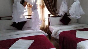 A hotel room with two beds, each with white bedding and red throw pillows. There are white curtains and a sheer canopy over the beds. - Rio Home stay (Haputhale)