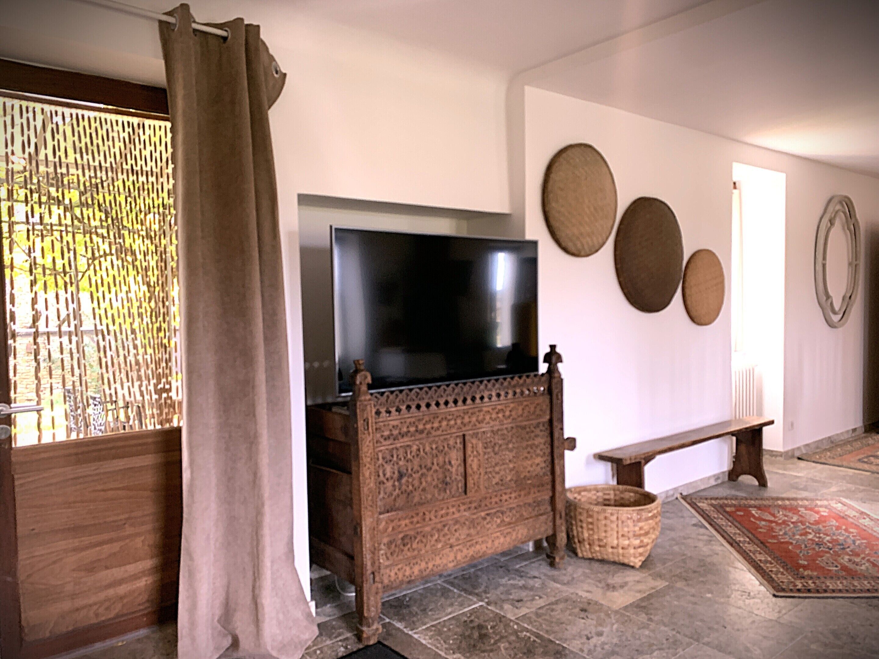 A living room with a television on a wooden cabinet, a bench, and a woven basket.