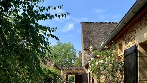A stone building with a gravel path leading to a wooden gate.