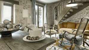A rustic interior with a stone wall, wooden staircase, and a dining area with a table set for a meal.