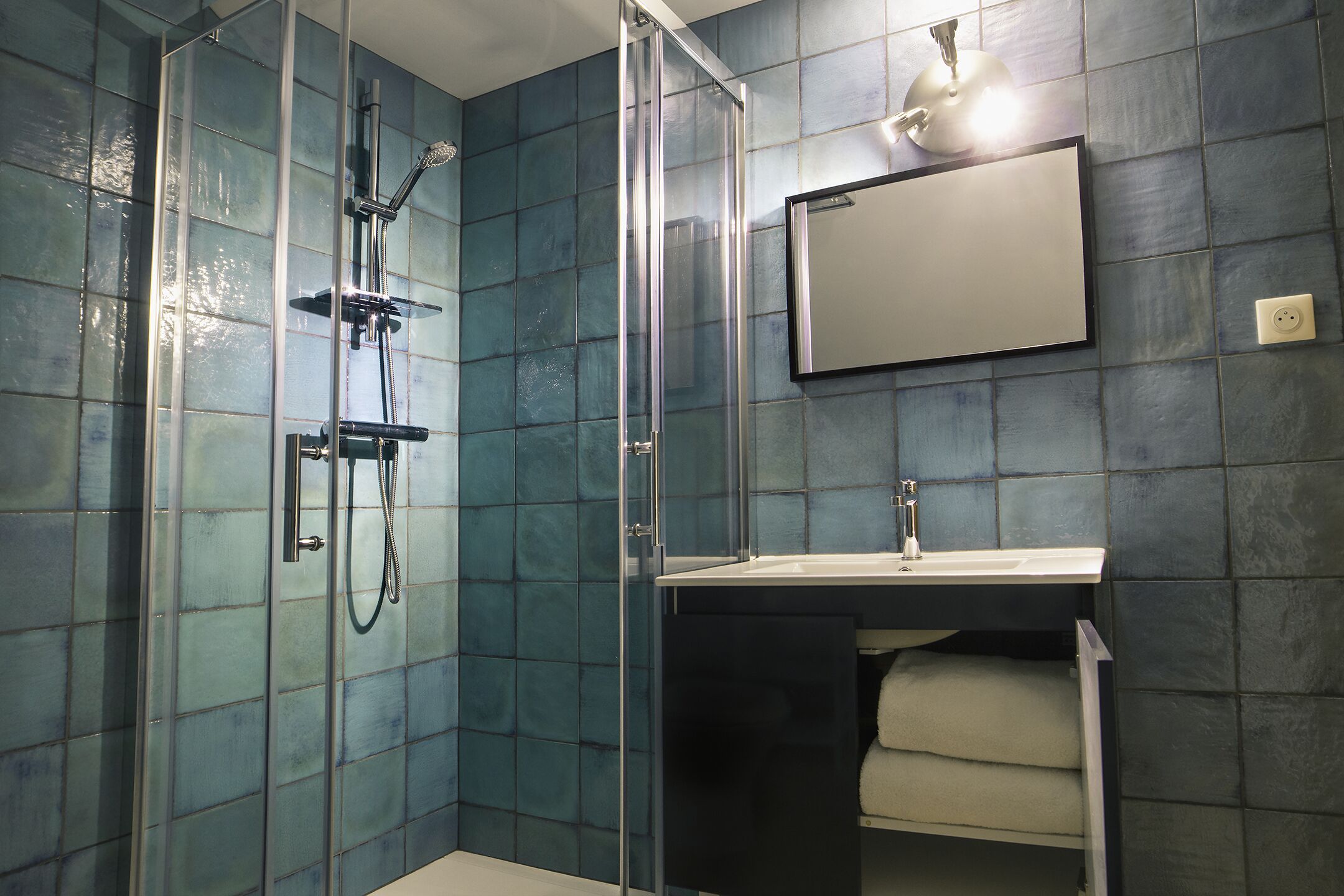 Une salle de bain avec une douche à parois de verre, un lavabo et un miroir.