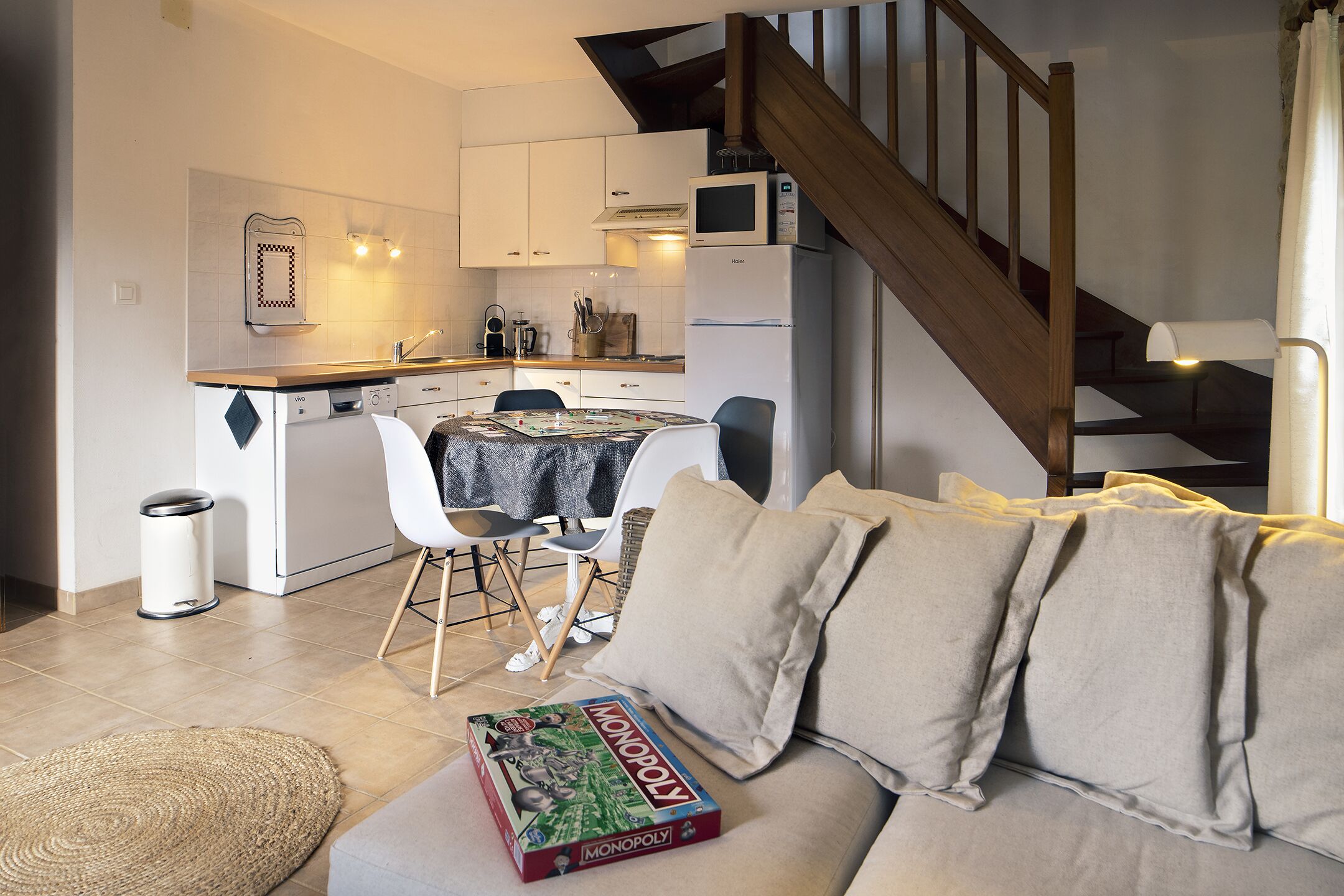 Une cuisine moderne avec des meubles blancs, un four à micro-ondes et un coin repas comprenant une table et des chaises.