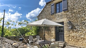A stone building with a patio area featuring a table, chairs, and a large umbrella.