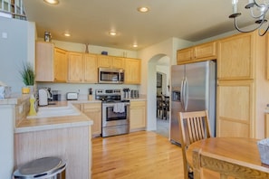 Eine moderne Küche mit Holzschränken, Edelstahlgeräten und einem Essbereich mit Holztisch und Stühlen.