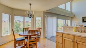 Una cocina amplia con armarios de madera, una mesa de comedor con sillas y ventanas grandes que ofrecen vistas al exterior.