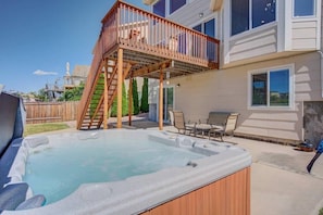 Ein Garten mit Whirlpool, Holzterrasse und Gartenmöbeln.