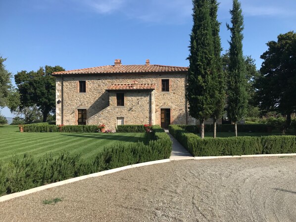 A stone building with a tiled roof, a paved driveway, and well-manicured lawns. - BelSentiero (Castiglione d'Orcia)