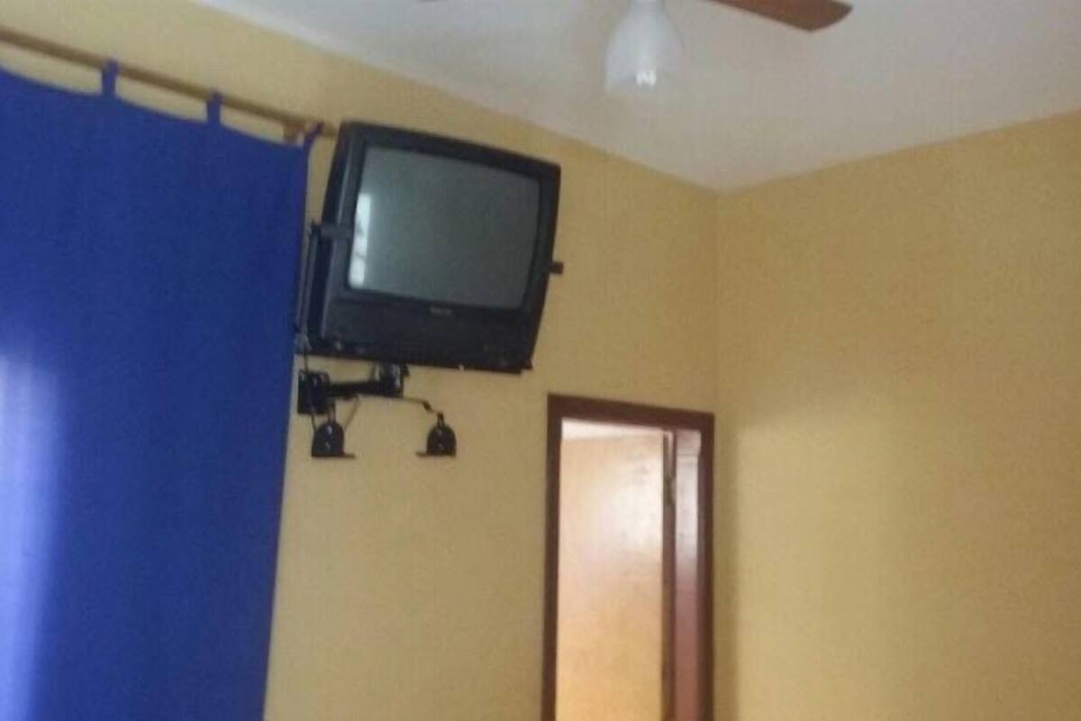 A room with a television mounted on the wall, a blue curtain, and a wooden door.