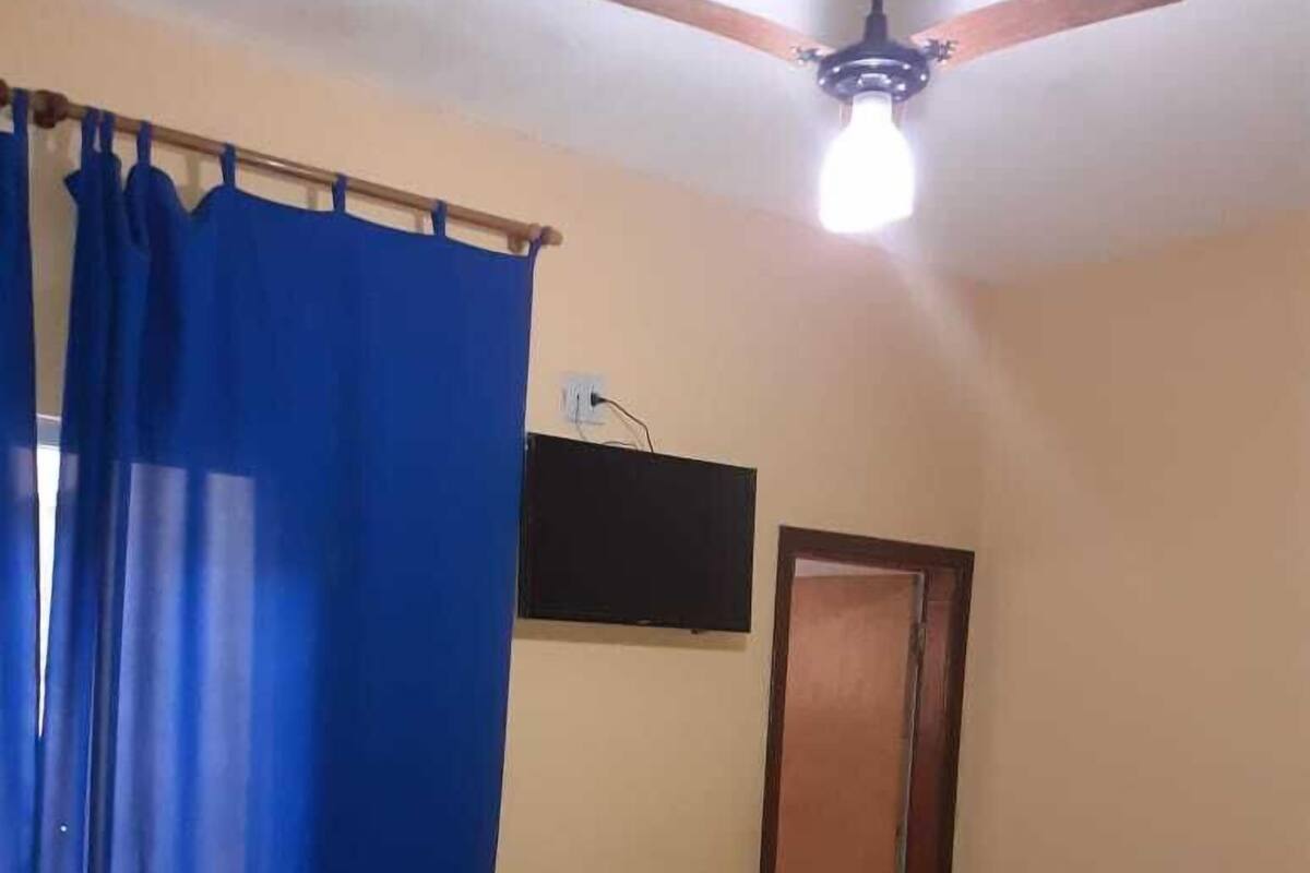 A bedroom with a bed, a ceiling fan, a television, and a door.