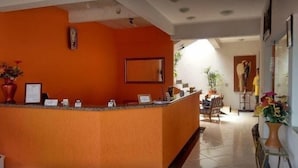 En receptionsområde med orange væg, en receptionsdisk og en stol.