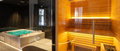 Un moderno spa con sauna, una bañera de hidromasaje con paredes de vidrio y un banco de madera.
