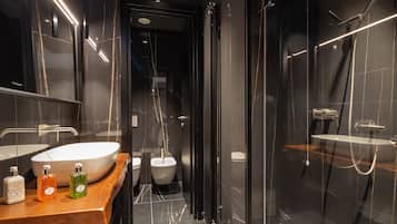 Un baño moderno con un lavamanos grande, bidé y ducha con cerramiento de vidrio.