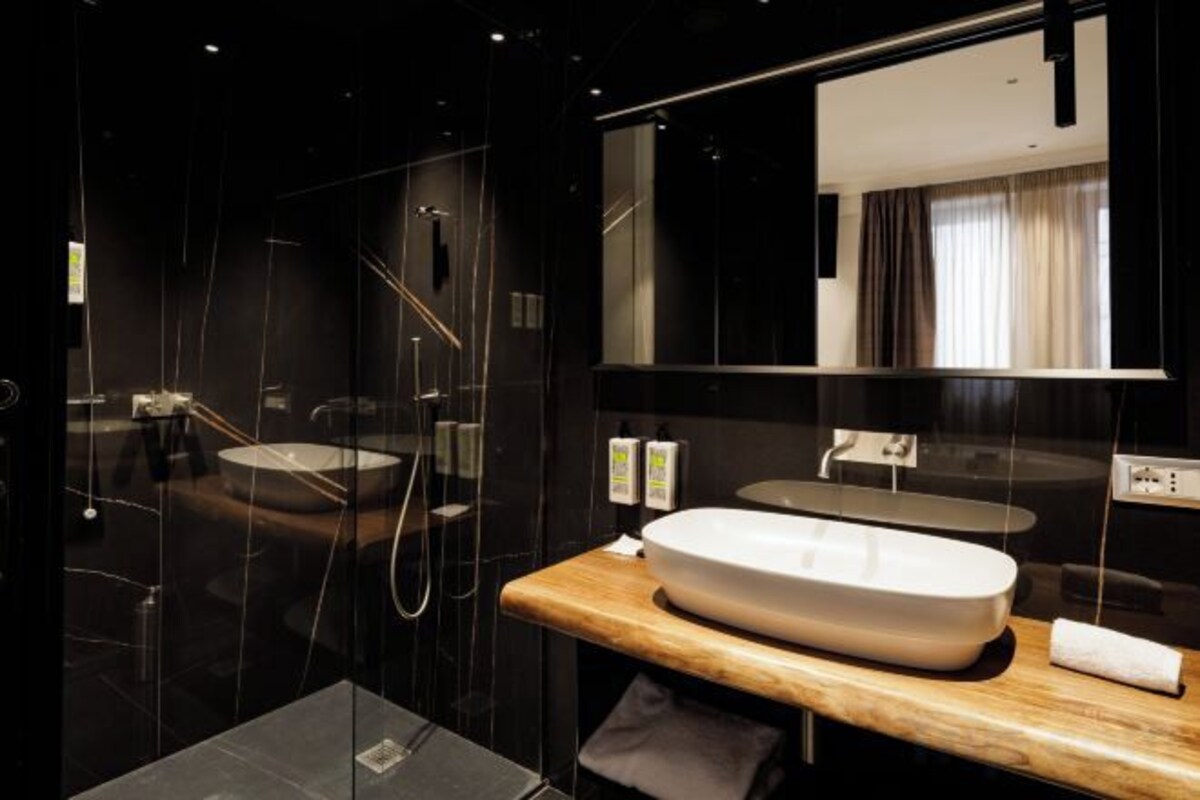 A modern bathroom with a large mirror, a wooden vanity, and a glass shower enclosure.