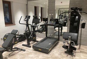 Un gimnasio moderno con diverso equipo de ejercicio, incluyendo cintas de correr, bicicletas estáticas y máquinas de pesas.
