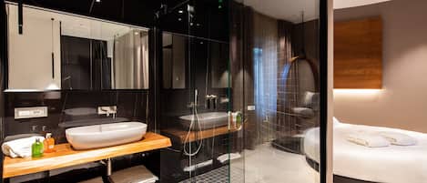 A modern bathroom with a large sink, mirror, and shower area.
