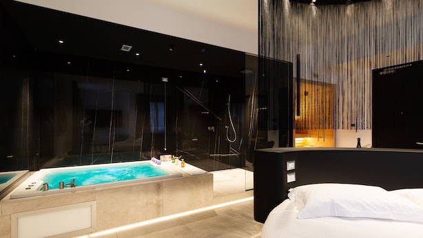 A modern hotel room with a large bathtub, a separate shower area, and a bed with white linens. - The Corner Duomo Hotel (Milan)