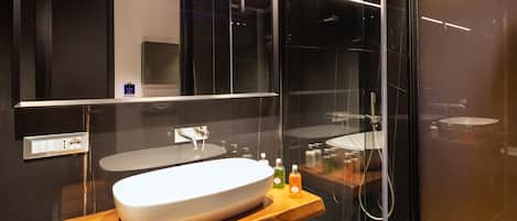 A modern bathroom with a large oval sink, a mirror, and a glass-enclosed shower.